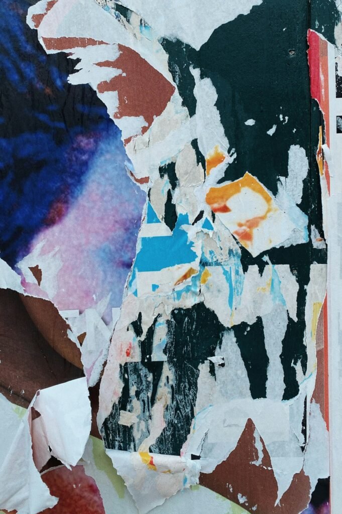 Large abstract collage of torn white, deep blue and rust-brown paper layers with ragged edges.